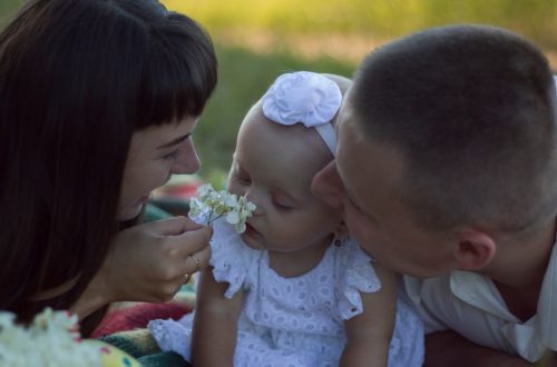 A loving family moment with parents and baby at a sunny outdoor picnic.