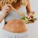Young woman in sports attire holding a fresh salad bowl, promoting a healthy lifestyle.